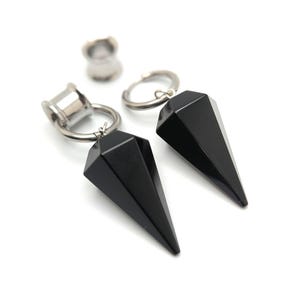 May include: A pair of black onyx teardrop earrings with silver hoops and plugs. The earrings are hanging from the hoops and plugs.