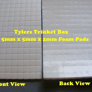 May include: Two views of a white foam pad. The front view shows a grid pattern of small squares. The back view shows a smooth surface with horizontal lines. The text "Tylers Trinket Box 5mm x 5mm x 2mm Foam Pads" is printed on the foam pad.