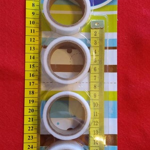 May include: Pack of four white hemming tape rolls with a yellow measuring tape. The packaging has a blue and white striped background with the text "Quick & Easy Hemming 4x (5m) tape" and "Craft Central Sewing".