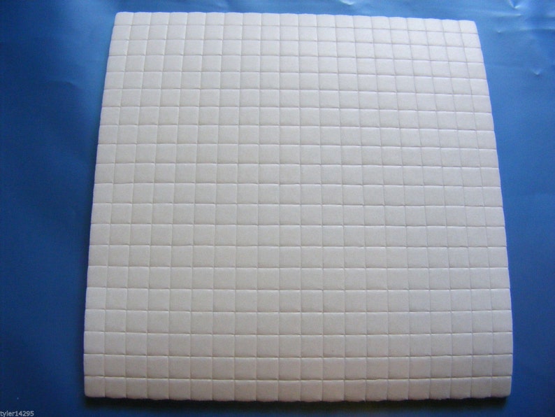 May include: A white sheet of adhesive-backed foam with a grid pattern. The foam is designed for crafts and DIY projects.