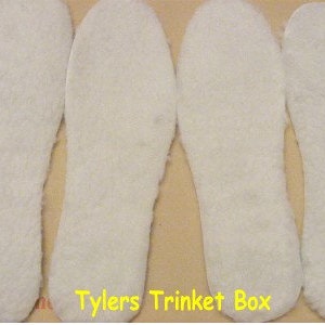 May include: Four white fleece shoe insoles. The insoles are shaped like feet and are designed to be placed inside shoes.
