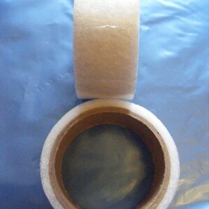 May include: Two rolls of white tape with a brown cardboard core. The tape is used for packaging and sealing.