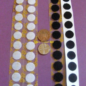 May include: Two strips of white and black 13mm hook and loop fasteners, also known as Velcro dots, coins, or circles. The strips are next to a British one pound coin for size comparison. The text "Tylers Trinket Box" is visible on the image.