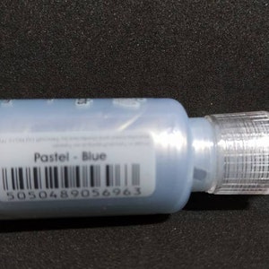 Puede incluir: Una peque&ntilde;a botella de pintura azul con una punta aplicadora de pl&aacute;stico transparente. La etiqueta dice "Pastel - Azul" y tiene un c&oacute;digo de barras con el n&uacute;mero 5050489056963.
