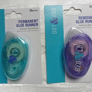 May include: Two packs of Dot & Dab glue runner, one purple and one blue. Both packs are labelled with the brand name and the type of glue runner, permanent or removable. Each pack contains 10 metres of glue runner.