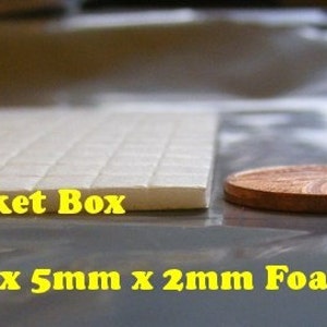May include: A close-up of a white foam sheet with the text "Tylers Trinket Box" printed on it. A penny is placed next to the sheet to show the scale. The text "5mm x 5mm x 2mm Foam Pads" is printed below the sheet.