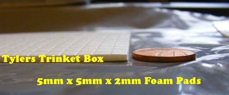 May include: A close-up of a white foam sheet with the text "Tylers Trinket Box" printed on it. A penny is placed next to the sheet to show the scale. The text "5mm x 5mm x 2mm Foam Pads" is printed below the sheet.