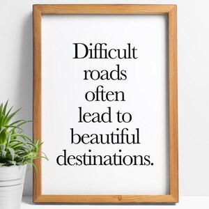 Puede incluir: Una impresión enmarcada con la cita "Difficult roads often lead to beautiful destinations." en texto negro sobre fondo blanco.