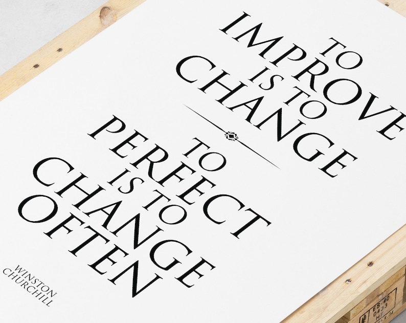 May include: Black and white typography print with the quote "To improve is to change, to perfect is to change often." attributed to Winston Churchill.