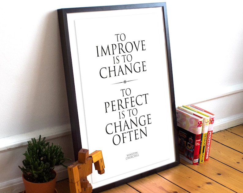 May include: Black and white framed print with a quote by Winston Churchill: "To improve is to change. To perfect is to change often."