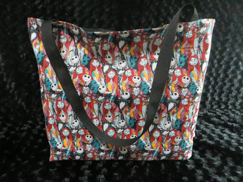 May include: A black tote bag with a colorful print of Jack Skellington and Sally from the Nightmare Before Christmas.