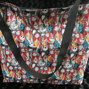 May include: A black tote bag with a colorful print of Jack Skellington and Sally from the Nightmare Before Christmas. The bag has two black straps.