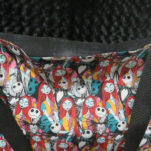 May include: Black tote bag with a colorful print of characters from the Nightmare Before Christmas. The print features Jack Skellington and Sally.