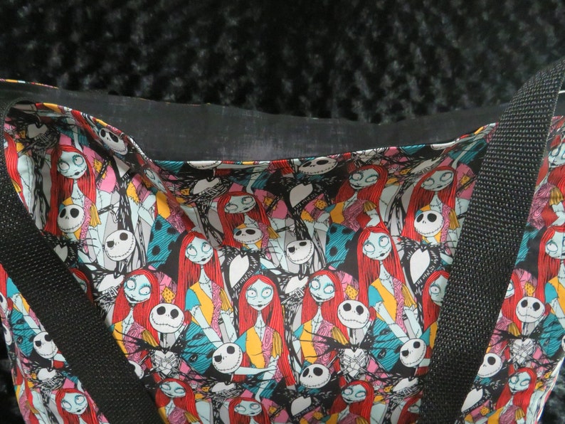 May include: Black tote bag with a colorful print of characters from the Nightmare Before Christmas. The print features Jack Skellington and Sally.