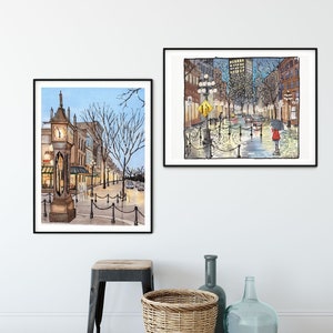 May include: Two framed watercolour paintings of city streets. The painting on the left shows a clock tower and buildings with a blue sky. The painting on the right shows a street with buildings and streetlights at night with a person walking with an umbrella.