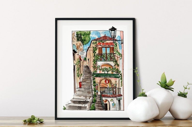 May include: Watercolor painting of a narrow street in a European city. The street is lined with buildings and has a set of stairs leading up to a building with a balcony. The building has a green awning with the text "Ristorante" on it. The painting is framed in a black frame.