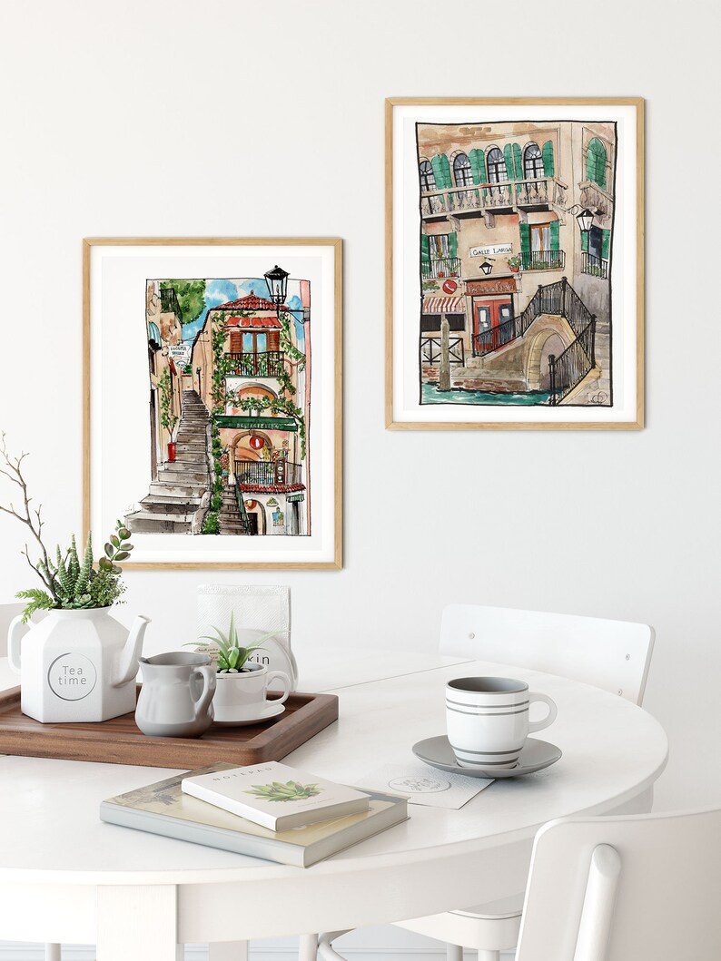 May include: Two watercolor paintings of buildings in Venice, Italy. The first painting shows a narrow street with a staircase leading up to a building with a red door and green plants. The second painting shows a canal with a bridge and a building with a sign that says "Galle Lavoro".