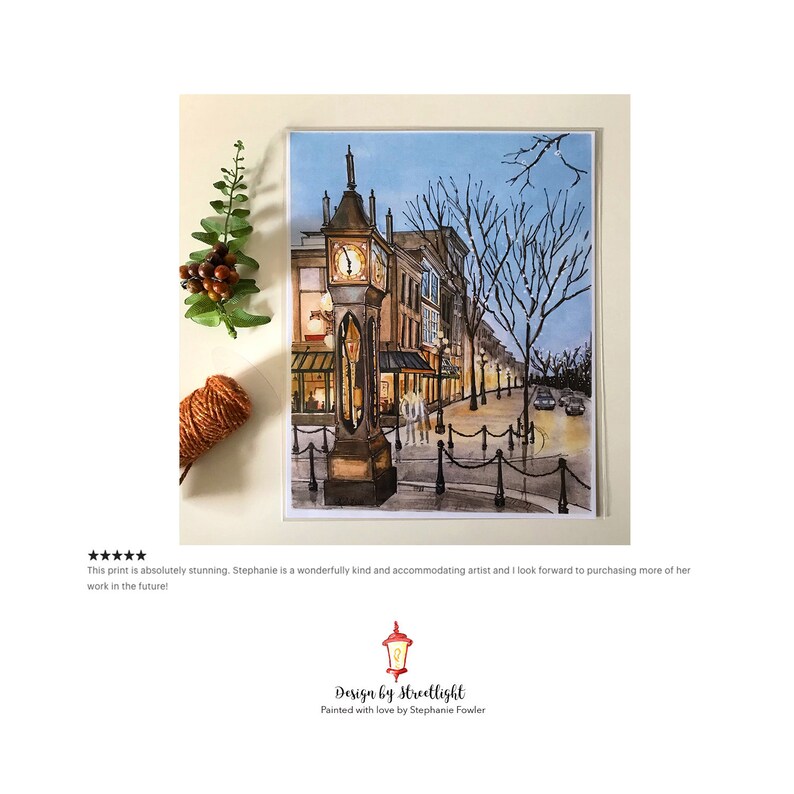 May include: Watercolour painting of a street scene with a clock tower in the foreground. The clock tower is lit up and there are buildings and trees in the background. The street is empty and there are cars parked on the side of the road. The painting is titled "Design by Streetlight" and is signed by Stephanie Fowler.