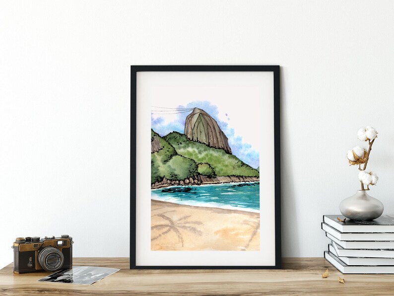 May include: A watercolor painting of a beach scene with a mountain in the background. The mountain is green and brown, and the beach is sandy with palm trees in the foreground. The water is blue and the sky is light blue with white clouds.
