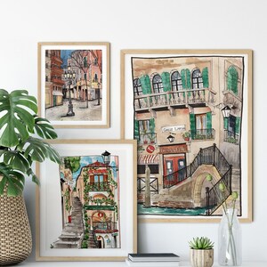 May include: Three framed watercolor paintings of Italian cityscapes. The paintings depict narrow streets, buildings with colorful facades, and charming details like balconies, stairs, and streetlights.