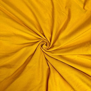 May include: A close-up of a smooth, yellow fabric with a swirling pattern. The fabric is soft and has a subtle sheen.