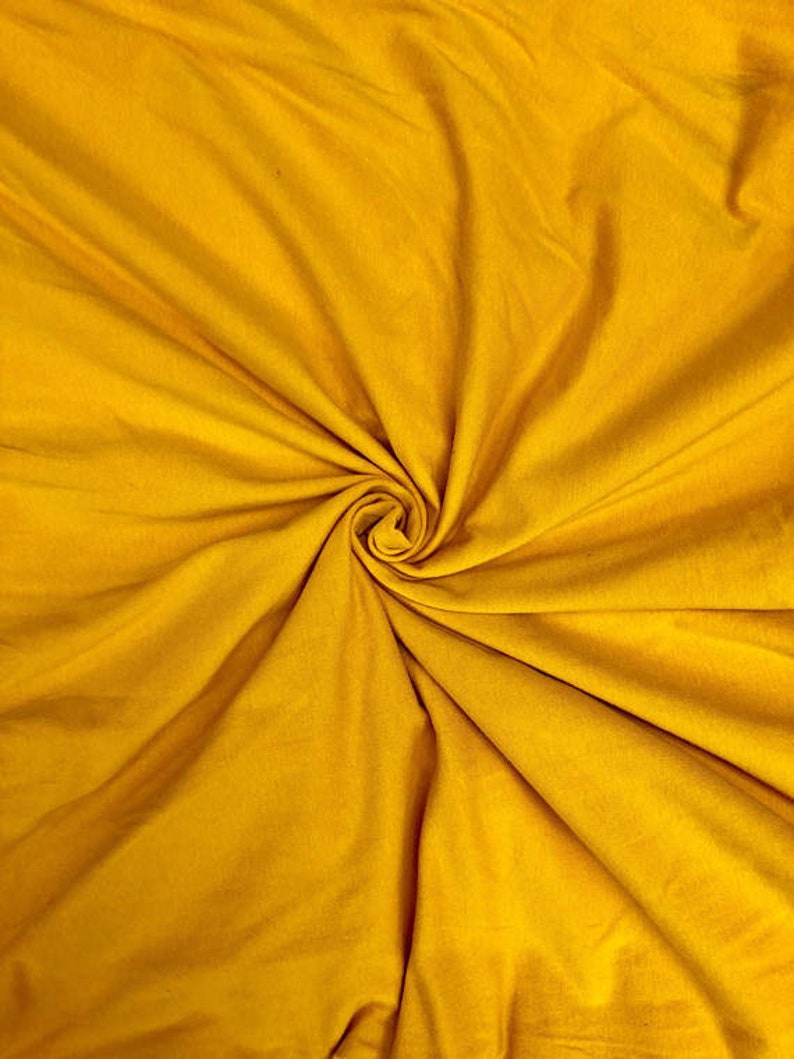 May include: A close-up of a smooth, yellow fabric with a swirling pattern. The fabric is soft and has a subtle sheen.