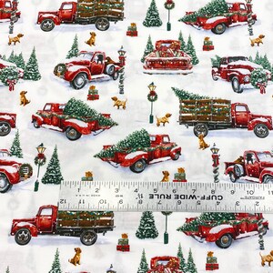 K&ouml;nnte beinhalten: Wiederholendes Muster auf wei&szlig;em Stoff mit roten Oldtimer-Trucks, die Weihnachtsb&auml;ume und Geschenke transportieren. Kleine braune Hunde und gr&uuml;ne Weihnachtsb&auml;ume sind &uuml;ber das Design verstreut. Schnee bedeckt den Boden und die Trucks.