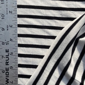 May include: Black and white striped fabric with a ruler measuring 12 inches. The fabric is a soft, stretchy knit.