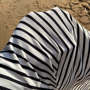 May include: Close-up of a white and black striped fabric with a soft, textured feel.