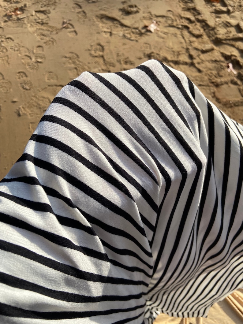 May include: Close-up of a white and black striped fabric with a soft, textured feel.