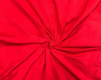 May include: A close-up of a bright red fabric with a smooth texture. The fabric is folded and twisted, creating a swirling pattern.