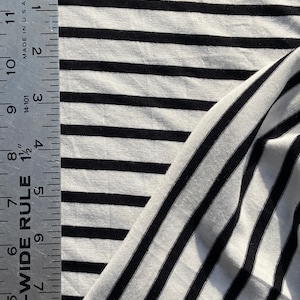 May include: White fabric with black stripes. The fabric is folded and a ruler is visible on the left side of the image. The ruler is marked in inches and shows measurements from 4 to 12 inches.