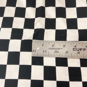 May include: Black and white checkered fabric with a ruler measuring 5 inches across the fabric.