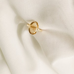 May include: A gold ring with a large, oval-shaped, light brown gemstone.