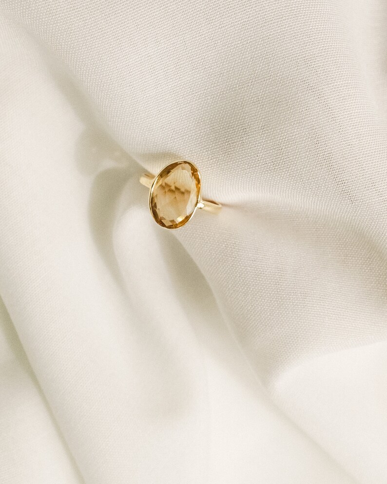 May include: A gold ring with a large, oval-shaped, light brown gemstone.