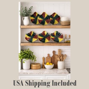 May include: Six decorative ceramic plates with a unique leaf-like shape, featuring a vibrant color palette of yellow, green, and burgundy. The plates are displayed on wooden shelves in a kitchen setting, adding a touch of artistic flair to the decor.
