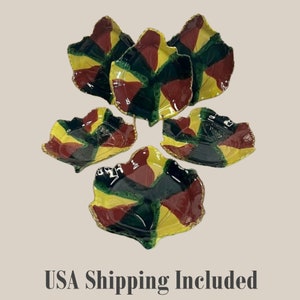 Może przedstawiać: Zestaw pięciu ceramicznych talerzyków w kształcie liści. Każdy talerzyk ma unikalny wzór z żółtych, zielonych i brązowych segmentów. Krawędzie są lekko podniesione, a wykończenie błyszczące.