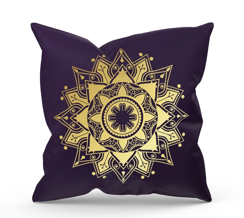 May include: A purple pillow with a gold mandala design. The mandala is intricate and detailed, with a central flower and radiating patterns.