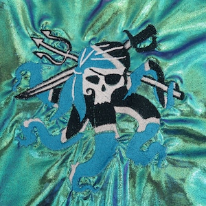 May include: Embroidered patch featuring a skull with an eyepatch, a trident, and a sword, all surrounded by blue and white waves on a turquoise iridescent fabric.