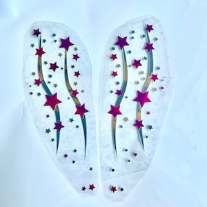 Op de afbeelding: Twee transparante plastic vellen met zilveren en roze sterontwerpen. De sterren zijn gerangschikt in een patroon van vallende sterren.