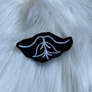 May include: Black fabric patch with a white embroidered design of a tree with roots.