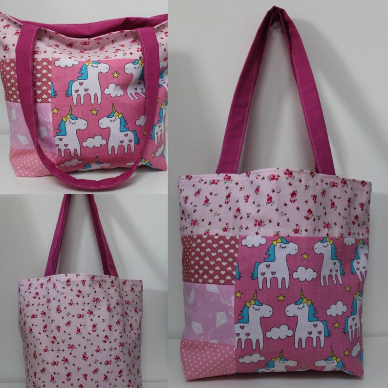 Puede incluir: Bolso tote rosa patchwork con asas magenta. El bolso presenta un estampado de unicornios con unicornios blancos, crines azules y cuernos dorados sobre un fondo rosa. Otras secciones tienen estampados florales y geom&eacute;tricos.