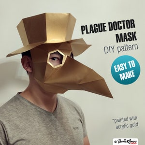 May include: A gold-painted papercraft plague doctor mask with a long beak and eye holes. The mask is worn by a person with a grey shirt. The text "PLAGUE DOCTOR MASK DIY pattern EASY TO MAKE *painted with acrylic gold" is visible in the image.