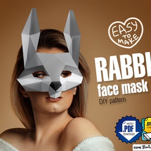 Może przedstawiać: Geometryczna szara maska na twarz królika. Maska wykonana jest ze złożonego papieru lub kartonu, z poligonalnym wzorem. Tekst na obrazku brzmi "EASY TO MAKE" i "RABBIT face mask DIY pattern".