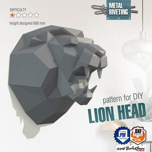 Puede incluir: Un modelo de papel 3D gris de una cabeza de león, diseñado para montaje DIY. El modelo tiene 600 mm de altura y requiere remaches metálicos. La imagen incluye el texto "pattern for DIY LION HEAD" y "METAL RIVETING".