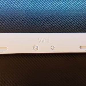 May include: A white Wii sensor bar with the word "Wii" embossed on the front. The bar has a power button and two sensor sliders. The sensor bar is designed to sit above or below a television.