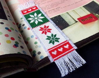 May include: A white bookmark with red and green embroidered snowflakes and hearts. The bookmark has white fringe on the bottom.