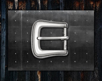 May include: A silver metal belt buckle with a decorative rope-like edge. The buckle is set against a dark grey metal panel with small, evenly spaced rivets. The background features a weathered wood texture.