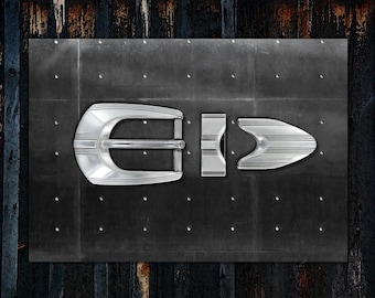 May include: A silver belt buckle with a rectangular shape and a smooth, polished finish. The buckle has a center bar with a raised design and a side release.