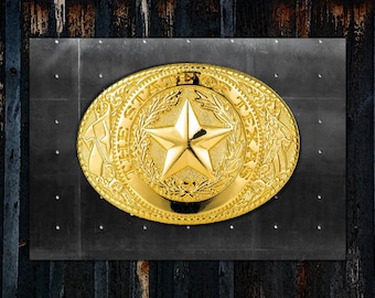 May include: A gold-colored belt buckle with a detailed design featuring the state of Texas seal. The seal includes a five-pointed star and the words "The State of Texas".